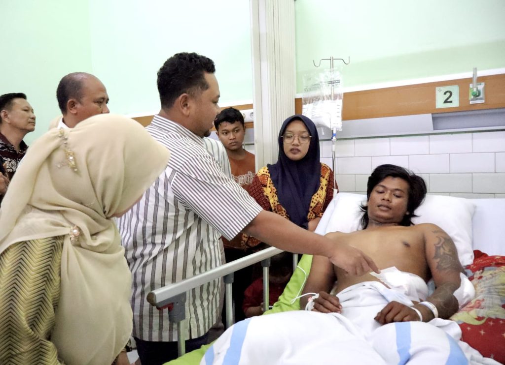 Gresik, siliwangpost1.com-  Pemerintah Kabupaten Gresik bersama jajaran Forkopimda menjenguk korban insiden pembacokan yang terjadi dua hari lalu di Kecamatan Panceng. Kunjungan dilakukan di RSUD Ibnu Sina Gresik, Minggu (01/03) untuk memastikan kondisi korban serta menjaga kondusivitas wilayah selama bulan suci Ramadan. Hadir dalam kunjungan tersebut Bupati Gresik Fandi Akhmad Yani, bersama Kapolres Gresik AKBP Ramadhan Nasution, Kapolsek Panceng, Kepala Dinas PMD, Kepala Dinas Kesehatan, Camat Panceng, Kepala Desa Campurejo, Kepala Desa Banyutengah, serta manajemen dan tim medis RSUD Ibnu Sina Gresik. Dalam kesempatan ini, bupati hadir langsung menyapa sekaligus memantau kondisi korban. Selain itu, Audiensi juga dilakukan dengan keluarga korban, tokoh masyarakat, serta perangkat desa setempat. Bupati Gresik Fandi Akhmad Yani hadir bersama jajaran terkait untuk melihat langsung perkembangan kesehatan korban sekaligus menyampaikan pesan damai kepada masyarakat. “Kami mendapatkan informasi dari Pak Kapolres. Bahkan tadi malam beliau masih di lapangan sampai waktu sahur. Hari ini kami bersama-sama menjenguk korban," ujar Bupati Yani. Ia menegaskan bahwa kehadiran pemerintah daerah bersama aparat merupakan bentuk komitmen memastikan kondisi korban dan situasi wilayah tetap terkendali. “Alhamdulillah berdasarkan laporan dokter yang menangani di rumah sakit, kondisinya membaik. Kemarin belum bisa makan kemudian masih dipasang infus. Tapi hari ini sudah bisa membaik dan bisa makan normal,” jelas Bupati Yani. Terkait kondisi korban, Bupati Yani menambahkan bahwa jika dalam satu hingga dua hari ke depan kondisi terus membaik, maka perawatan dapat dilanjutkan secara rawat jalan. Upaya meredam konflik juga terus berjalan, Bupati Yani menyampaikan bahwa proses perdamaian telah dilakukan. “Tadi malam sudah ada perdamaian yang dilaksanakan di balai desa oleh Pak Kapolres,” ungkapnya. Kepada masyarakat, Bupati Yani juga mengajak untuk menjaga situasi tetap aman dan kondusif selama Ramadan. “Kami mengajak kepada seluruh warga untuk menjaga kondusivitas kondisinya bulan suci Ramadan sangat tidak baik ketika ada peristiwa yang seperti ini. Kita harus menahan diri boleh melakukan kegiatan yang positif asalkan tidak mengganggu antar sesama. Dan yang paling penting adalah menjaga kondusivitas orang beribadah biar bisa mendapatkan rasa aman,” tegasnya. Sementara itu, Kapolr